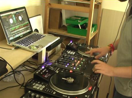photo of a person using two turntables a laptop computer and sound boards