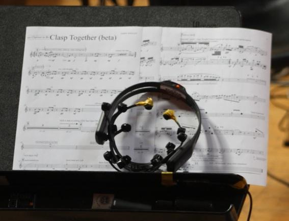 Image showing a 'neuroheadset' sitting on a music stand with sheet music for 'Clasp Together (beta)'